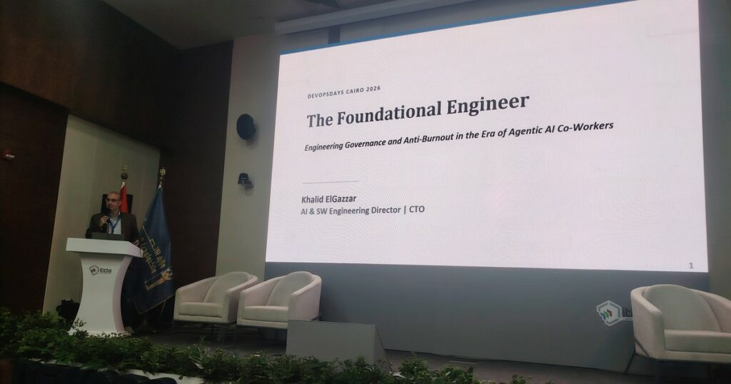 محاضرة المهندس التأسيسي في DevOpsDays Cairo 2026: المتحدث على المنصة وشريحة العنوان عن الحوكمة الهندسية في عصر الذكاء الاصطناعي الوكيلي